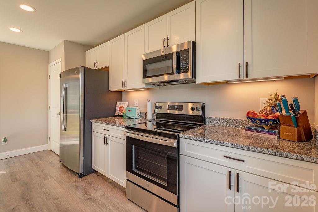 343 Garren Creek Road Fairview, NC 28730 - Photo 14 of 30 a kitchen with stainless steel appliances granite countertop a refrigerator stove and microwave with wooden floor