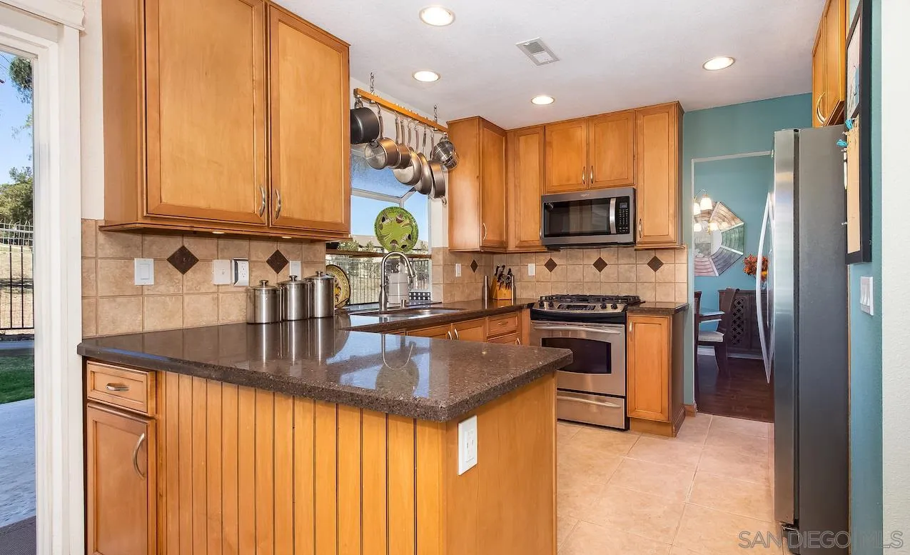 14140 Carmel Ridge Road San Diego, CA 92128 - Photo 7 of 17 a kitchen with stainless steel appliances granite countertop a refrigerator a stove and a sink with wooden floor