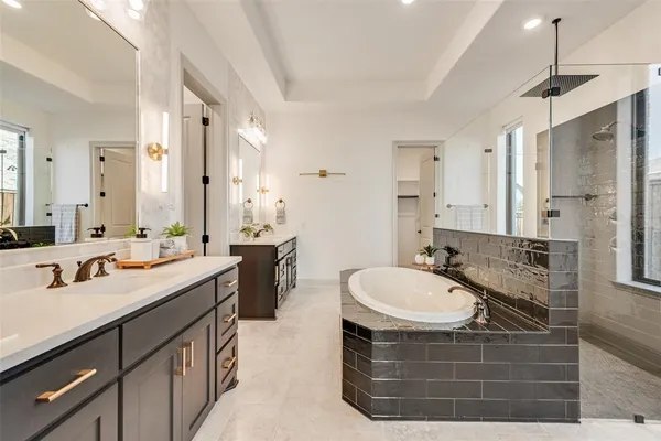 a bathroom with a sink double vanity granite tub shower and a mirror