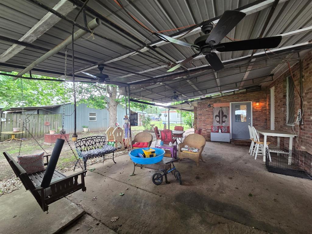 301 Old Plain Dealing Road Benton, LA 71006 - Photo 2 of 19 Expansive covered patio featuring a corrugated metal roof, multiple ceiling fans, exposed brick exterior, and a concrete slab