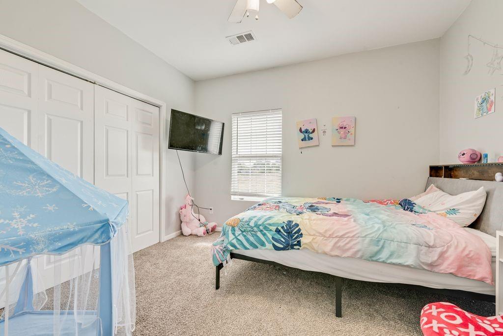 610 Ewing Road Ferris, TX 75125 - Photo 16 of 22 Light gray wall paint, textured carpet flooring, white bi-fold closet doors, and a ceiling fan with integrated lighting