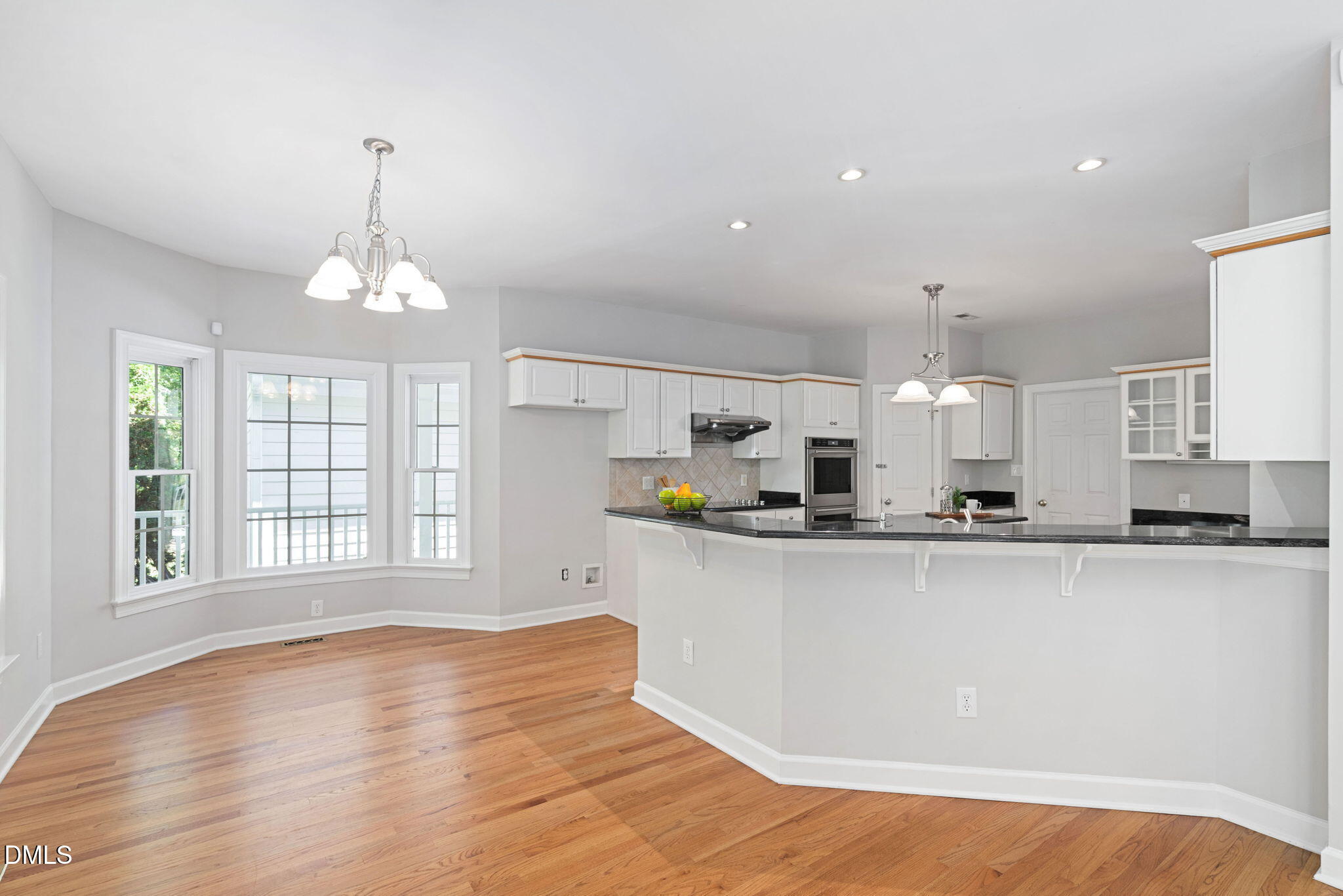 9916 Bonsal Crossing Road New Hill, NC 27562 - Photo 17 of 80 a large kitchen with granite countertop a stove a sink a window and white cabinets