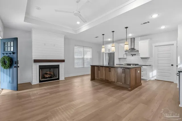 a kitchen with stainless steel appliances granite countertop a refrigerator a sink a stove and a wooden floors