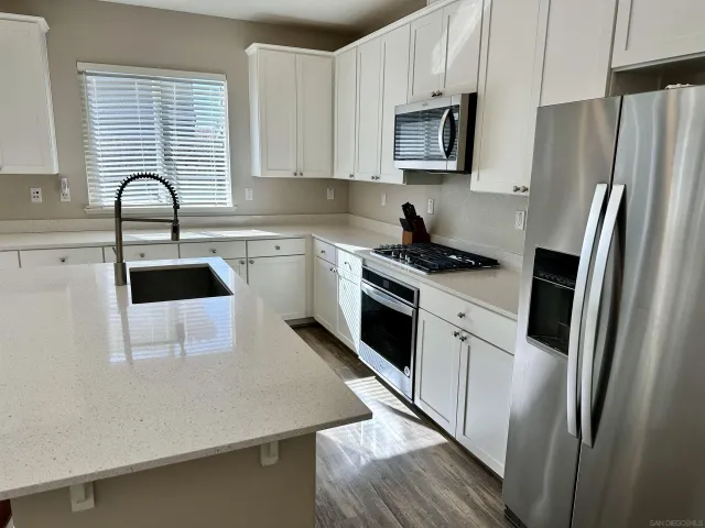 a kitchen with white cabinets stainless steel appliances and a sink