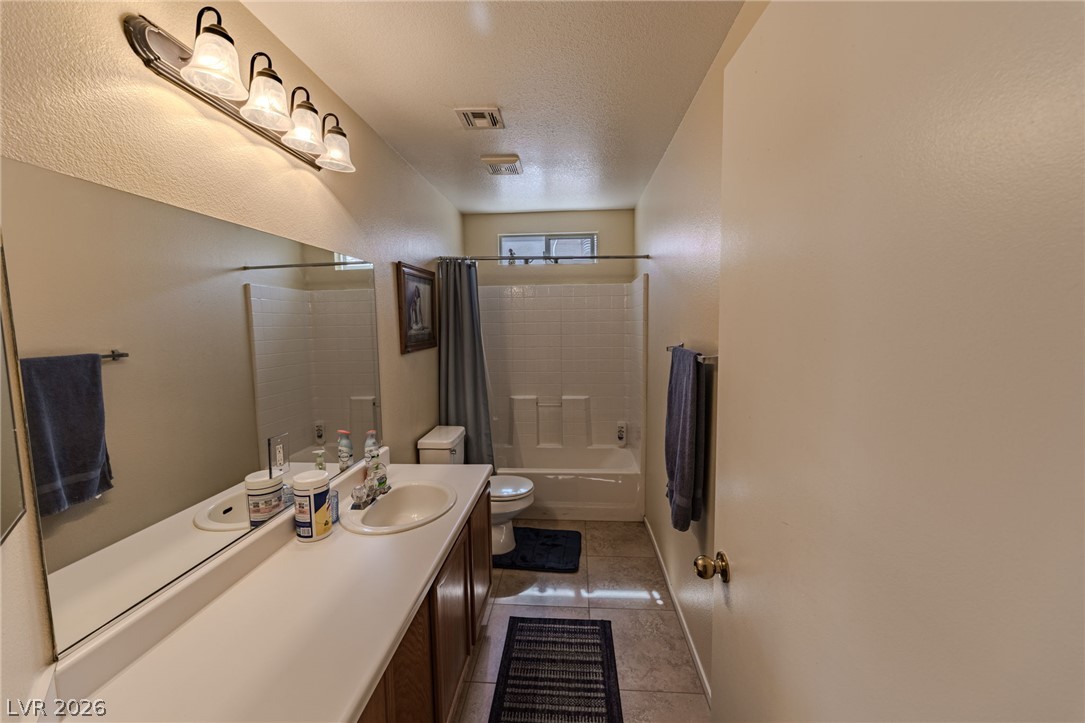 4994 Mascaro Drive Las Vegas, NV 89122 - Photo 16 of 30 Functional bathroom featuring a double vanity, a tiled tub-shower combination, and tile flooring.