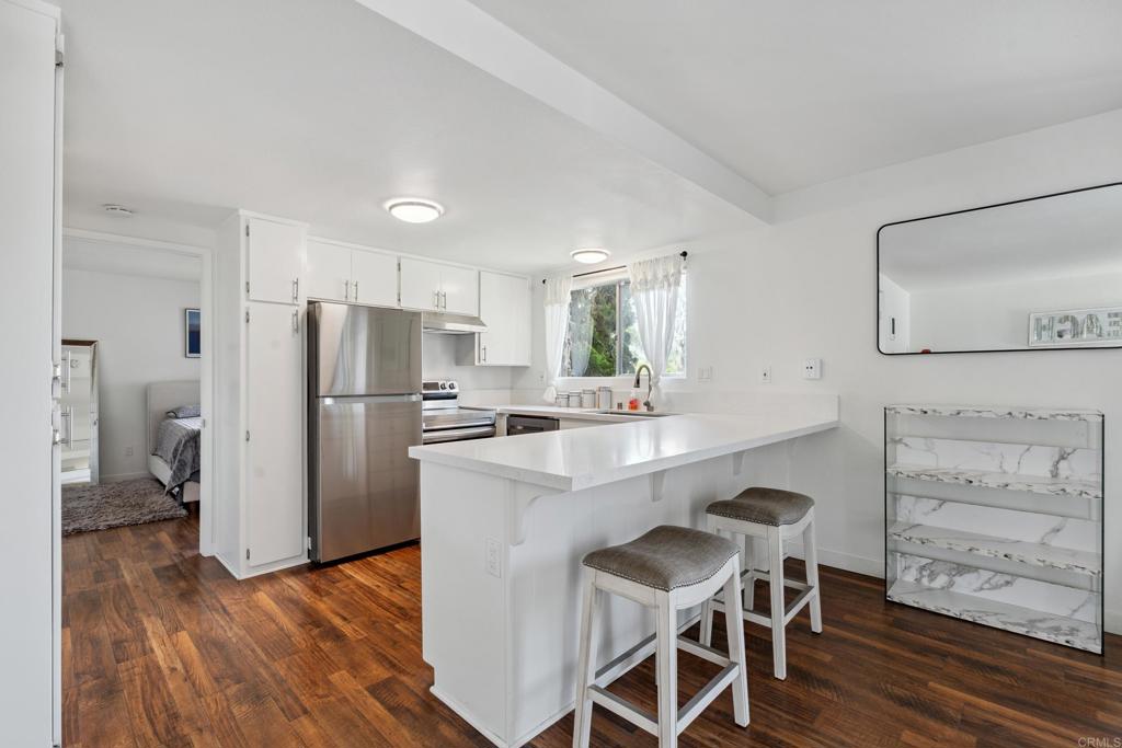 a kitchen with stainless steel appliances a refrigerator a stove a sink and white cabinets with wooden floor