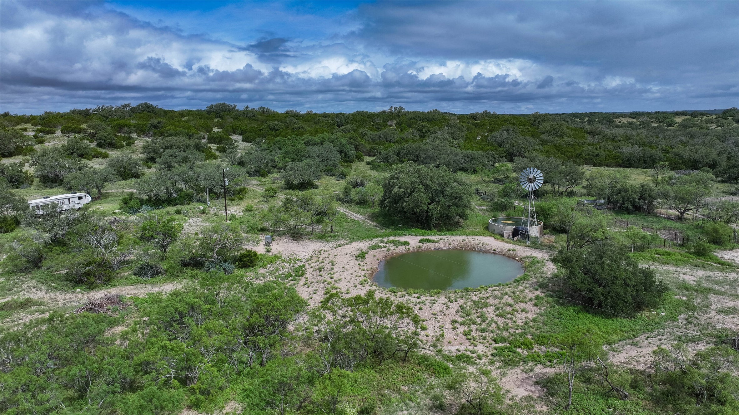 5 Dominion At Oak Ridge Junction, TX 76849 - Photo 25 of 34 Expansive natural landscape featuring a prominent pond and a classic windmill, surrounded by mature trees and varied vegetation