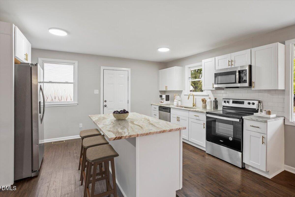 816 Peyton Street Raleigh, NC 27610 - Photo 3 of 29 a kitchen with stainless steel appliances kitchen island granite countertop a stove top oven a sink and white cabinets