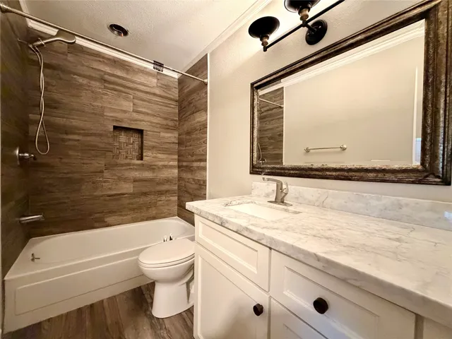 a bathroom with a granite countertop sink mirror vanity bathtub and toilet