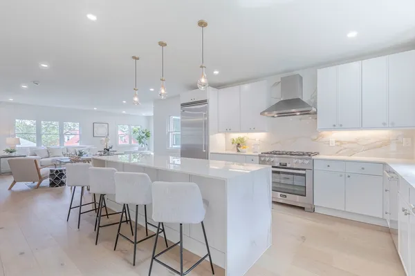 a kitchen with kitchen island granite countertop a sink a stove a dining table and chairs
