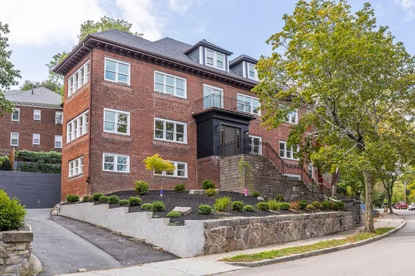 a front view of a residential apartment building with a yard and potted plants