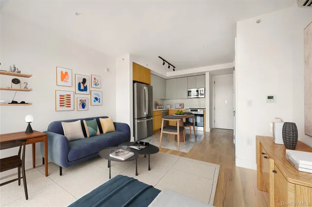 a kitchen with stainless steel appliances granite countertop a refrigerator a sink a stove and white cabinets with wooden floor