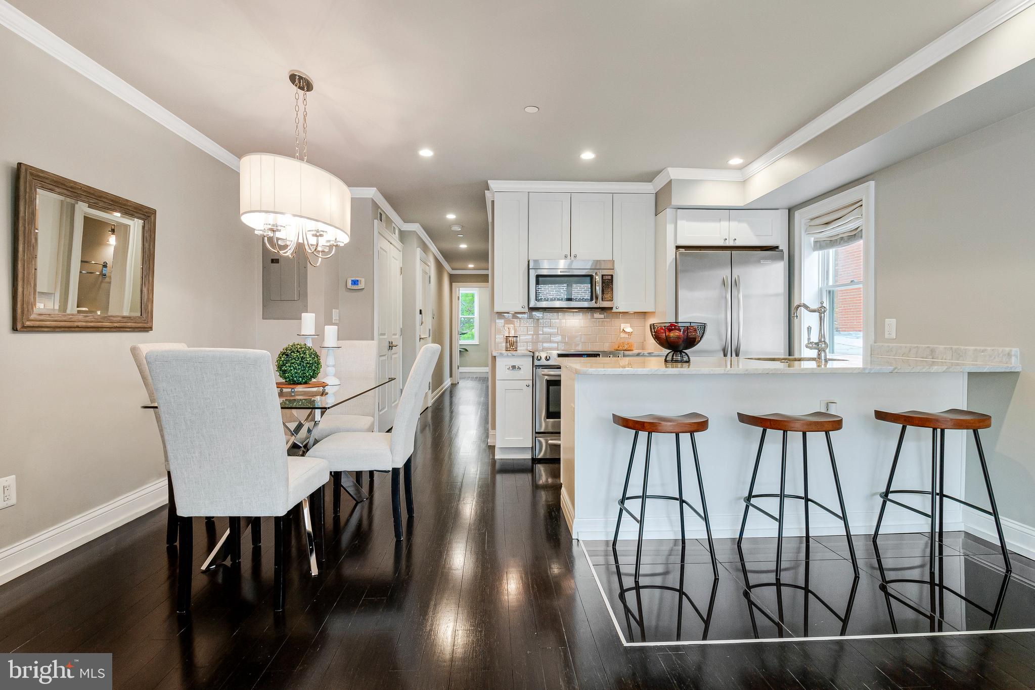 418 Seward Square Southeast, Unit 3 Washington, DC 20003 - Photo 4 of 16 a open dining room with stainless steel appliances kitchen island granite countertop a dining table chairs and a refrigerator