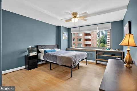 a spacious bedroom with a bed a chandelier and a large window