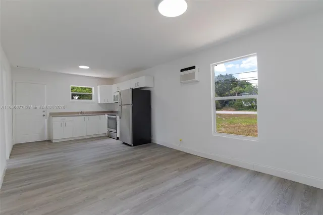 a view of an empty room with window and wooden floor