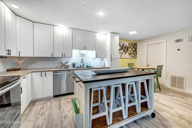 a kitchen with granite countertop a sink cabinets and wooden floor