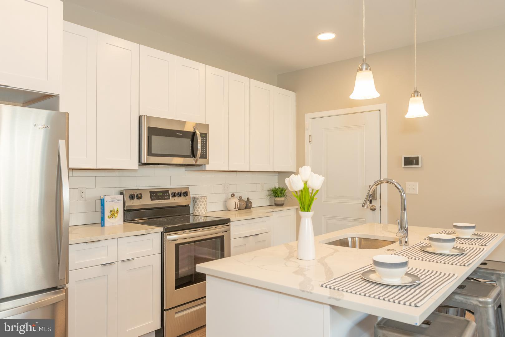 2220-28 Master Street, Unit 3 Philadelphia, PA 19121 - Photo 2 of 13 a kitchen with a sink a stove a table and chairs
