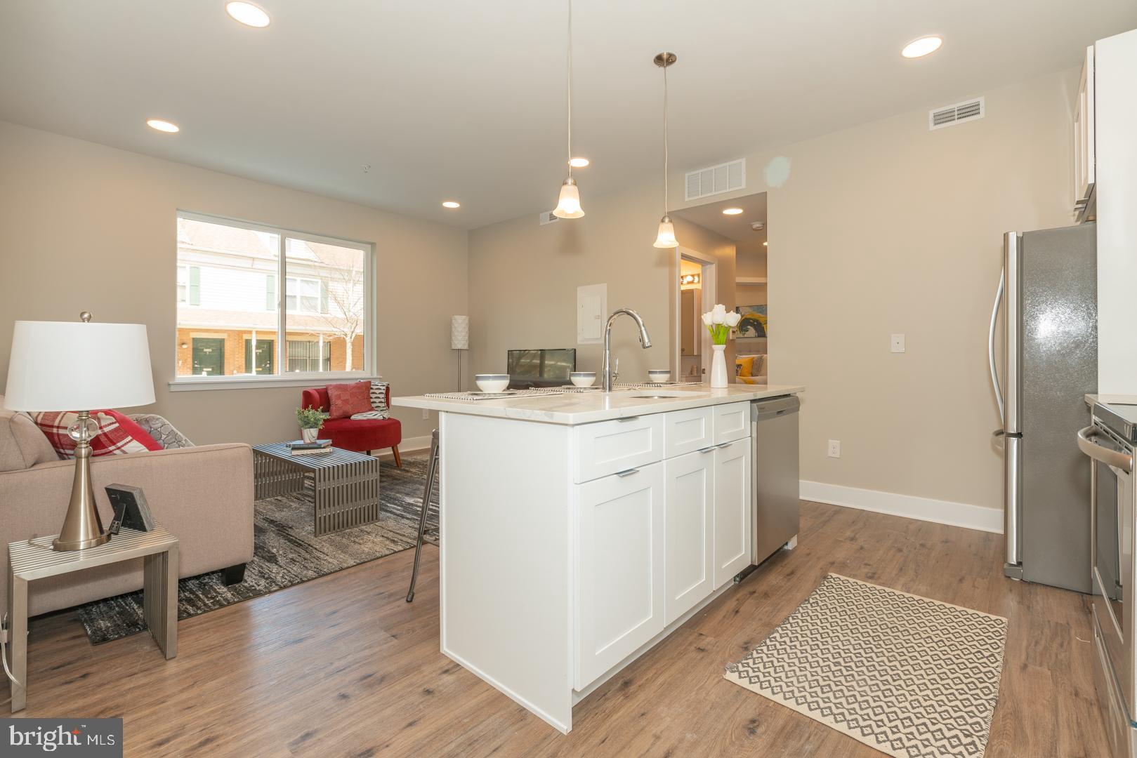 2220-28 Master Street, Unit 3 Philadelphia, PA 19121 - Photo 8 of 13 a kitchen with a sink dishwasher a dining table and chairs with wooden floor