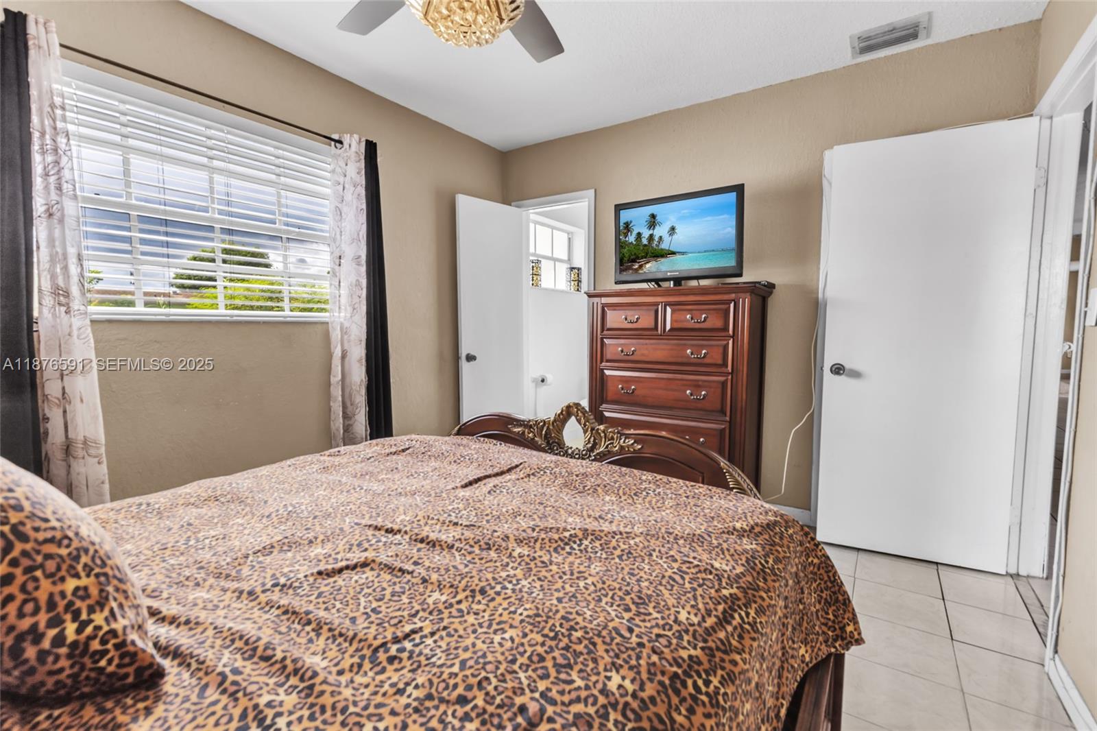 22270 Southwest 109th Avenue Miami, FL 33176 - Photo 21 of 48 a bedroom with a bed and a flat tv screen on dresser
