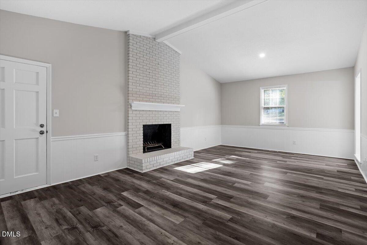 8233 Clear Brook Drive Raleigh, NC 27615 - Photo 12 of 28 a view of empty room with wooden floor and fireplace
