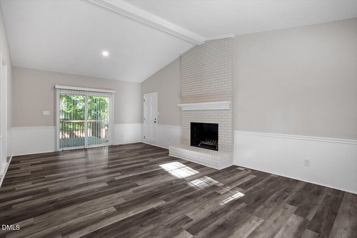 8233 Clear Brook Drive Raleigh, NC 27615 - Photo 13 of 28 a view of empty room with wooden floor and fireplace