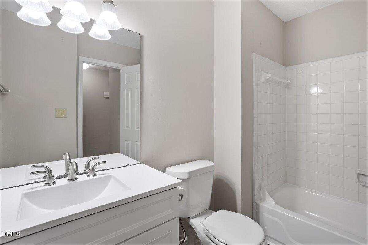 8233 Clear Brook Drive Raleigh, NC 27615 - Photo 22 of 28 a bathroom with a sink vanity granite toilet and a mirror