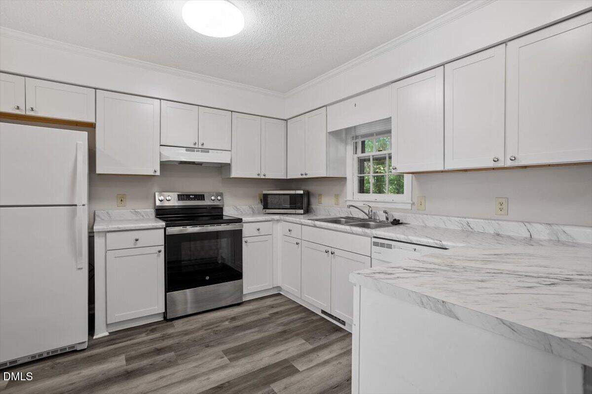 8233 Clear Brook Drive Raleigh, NC 27615 - Photo 7 of 28 a kitchen with granite countertop white cabinets and white appliances