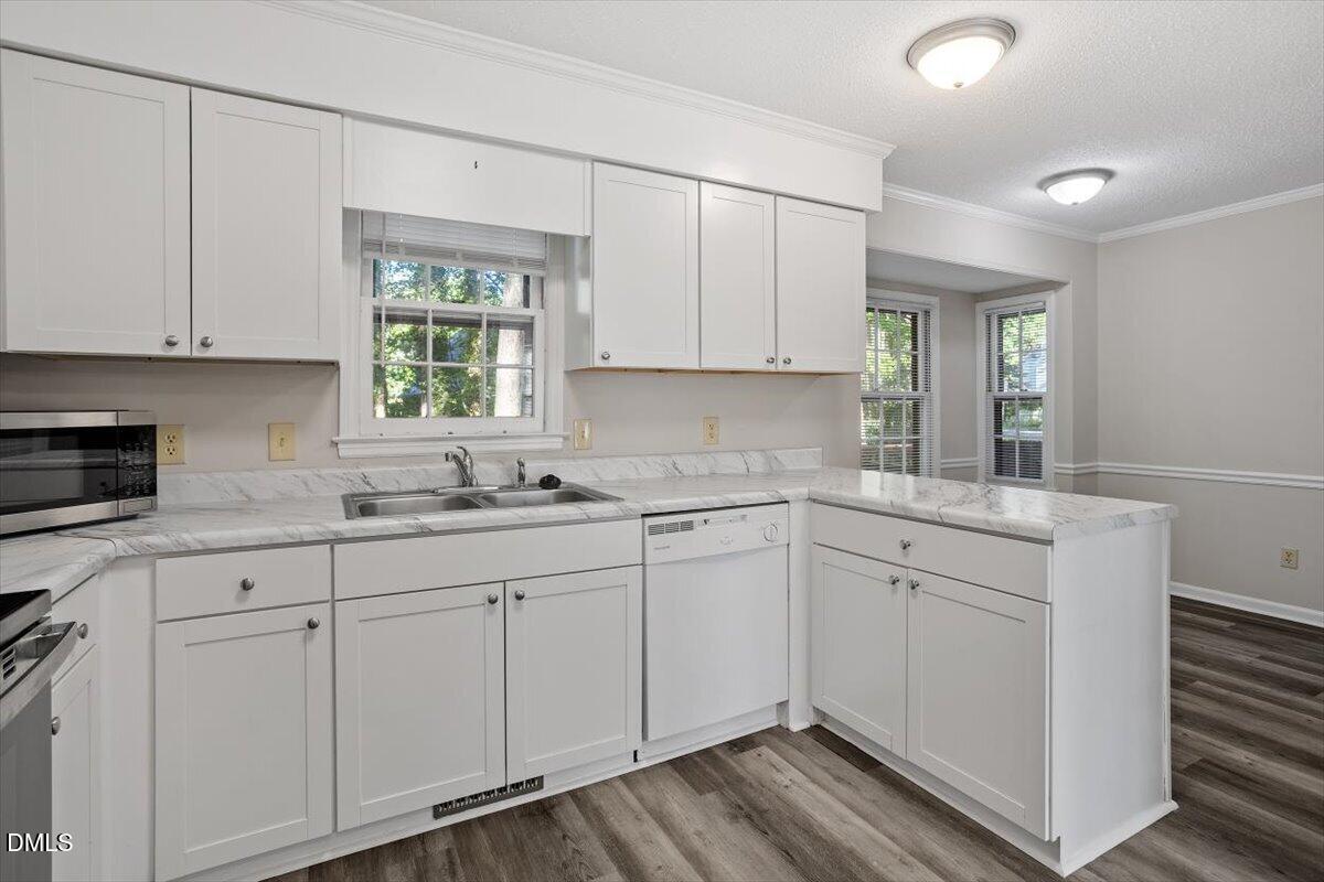8233 Clear Brook Drive Raleigh, NC 27615 - Photo 8 of 28 a kitchen with white cabinets white appliances sink and window