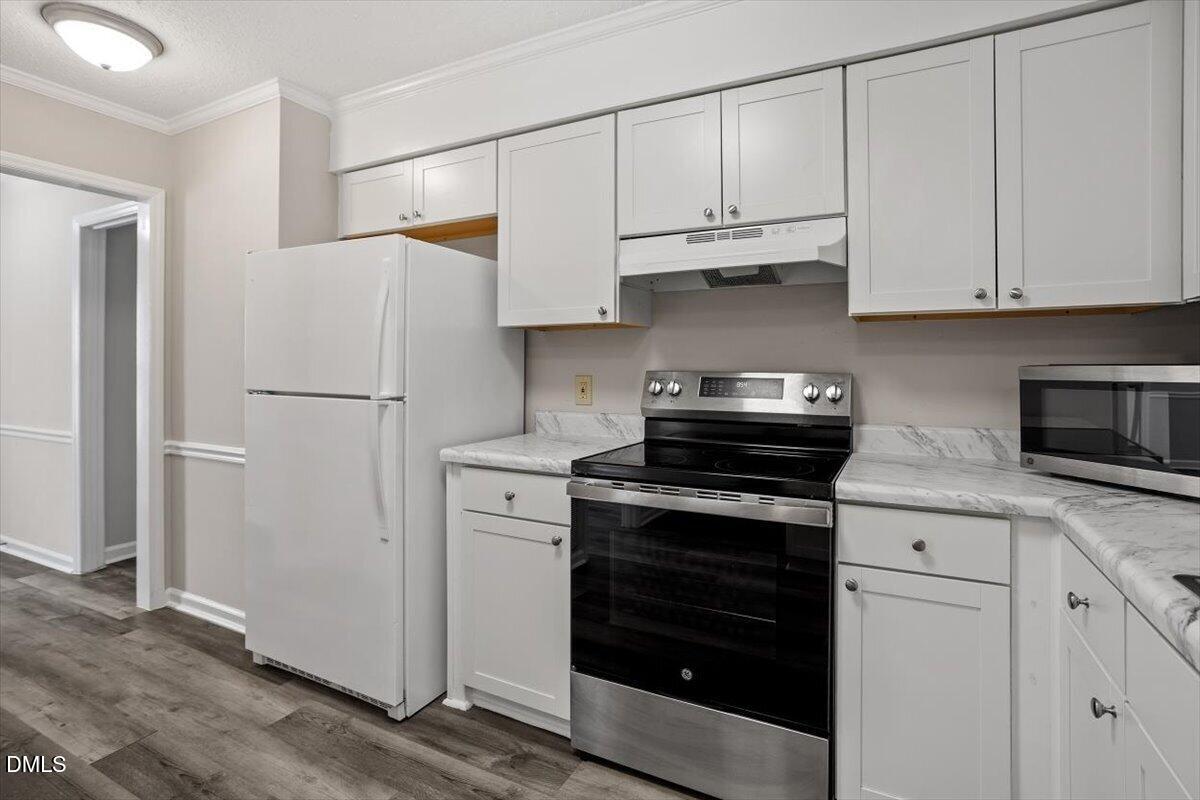 8233 Clear Brook Drive Raleigh, NC 27615 - Photo 9 of 28 a kitchen with white cabinets and black appliances