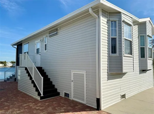 a front view of a house with stairs and wooden fence