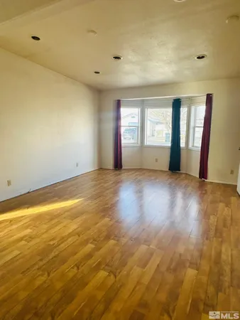 a view of an empty room with window and wooden floor