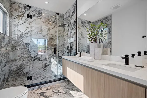 a bathroom with a granite countertop sink a toilet and shower