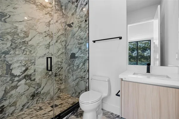 a bathroom with a granite countertop toilet and a sink