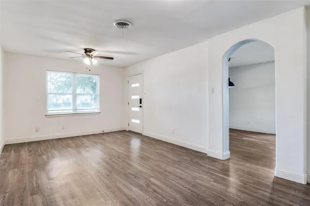 an empty room with wooden floor chandelier and windows