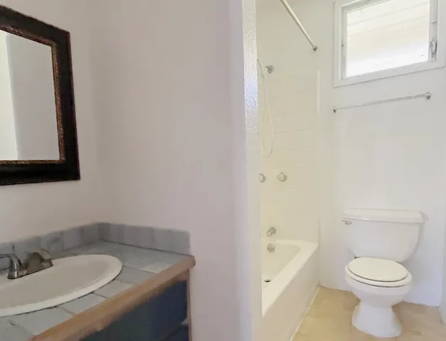 a bathroom with a granite countertop sink toilet and mirror