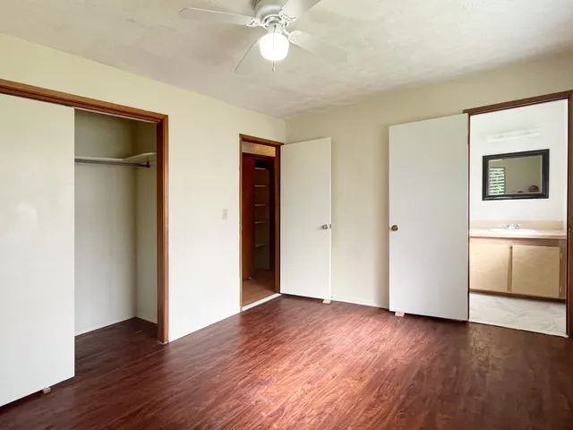 an empty room with wooden floor and a ceiling fan