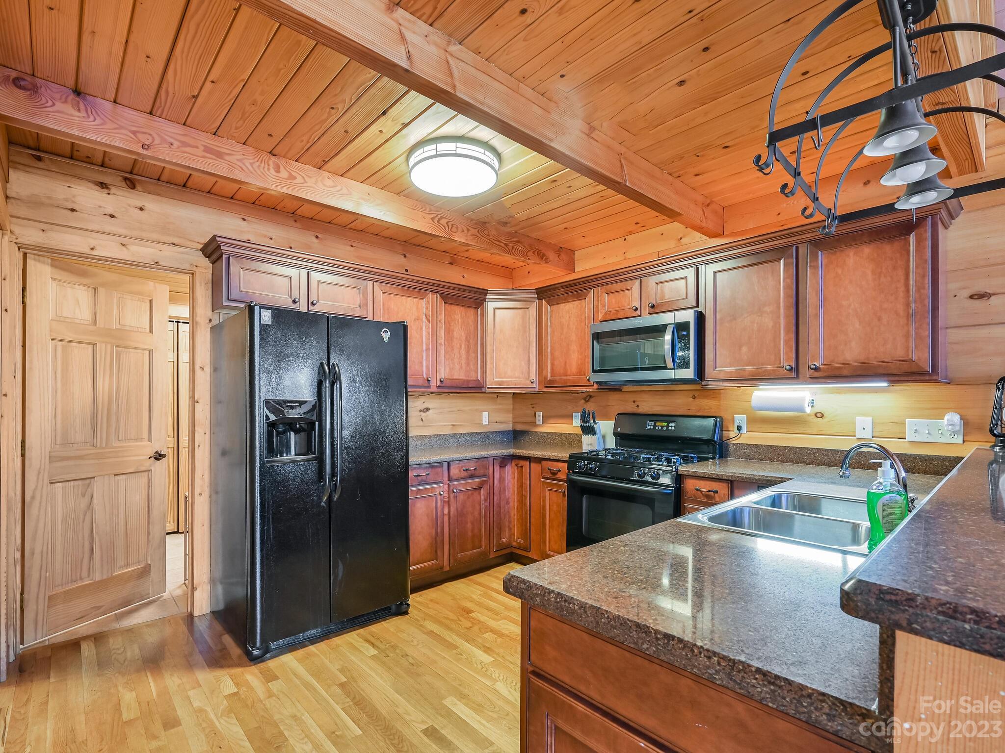 356 Panoramic Loop Maggie Valley, NC 28751 - Photo 4 of 24 a kitchen with stainless steel appliances granite countertop a refrigerator a stove and a sink with wooden cabinets