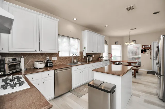 a kitchen with stainless steel appliances a stove a refrigerator and a oven with white cabinets