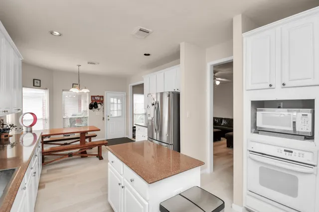 a large kitchen with stainless steel appliances lots of counter top space refrigerator and cabinets