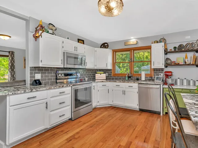 a kitchen with stainless steel appliances white cabinets and wooden floors