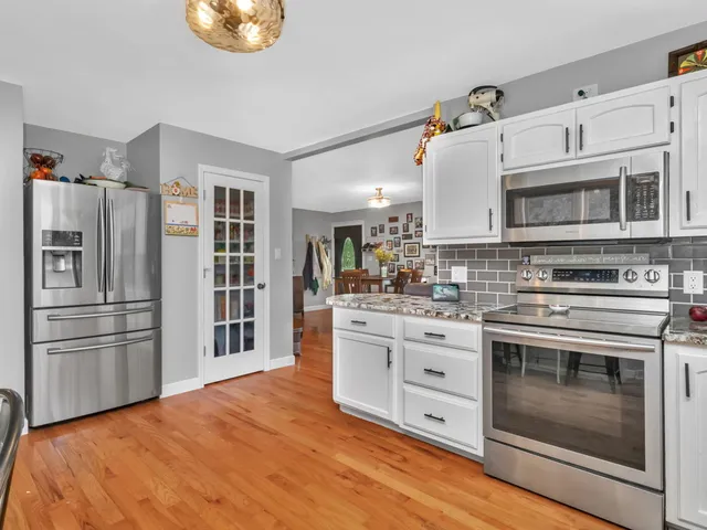 a kitchen with stainless steel appliances white cabinets and wooden floors