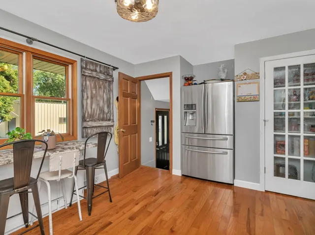 a kitchen with stainless steel appliances a refrigerator a stove a dining table and chairs with wooden floor