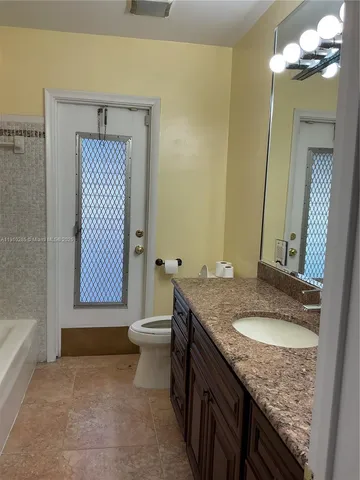a bathroom with a granite countertop sink a toilet and mirror