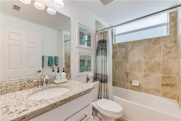 a bathroom with a granite countertop sink toilet and shower
