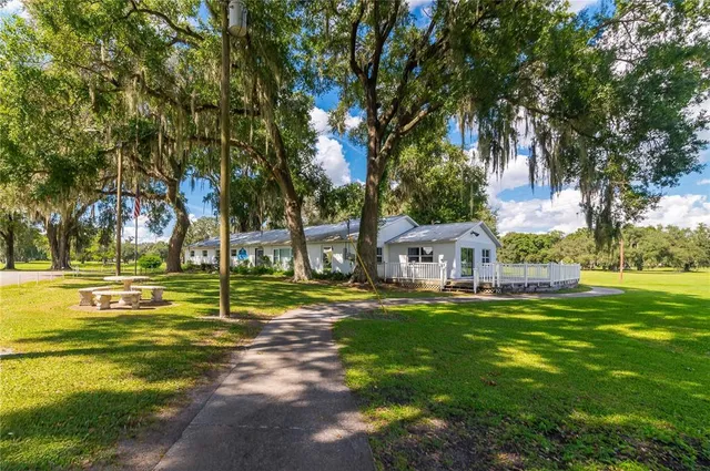 a view of a house with a big yard and palm trees