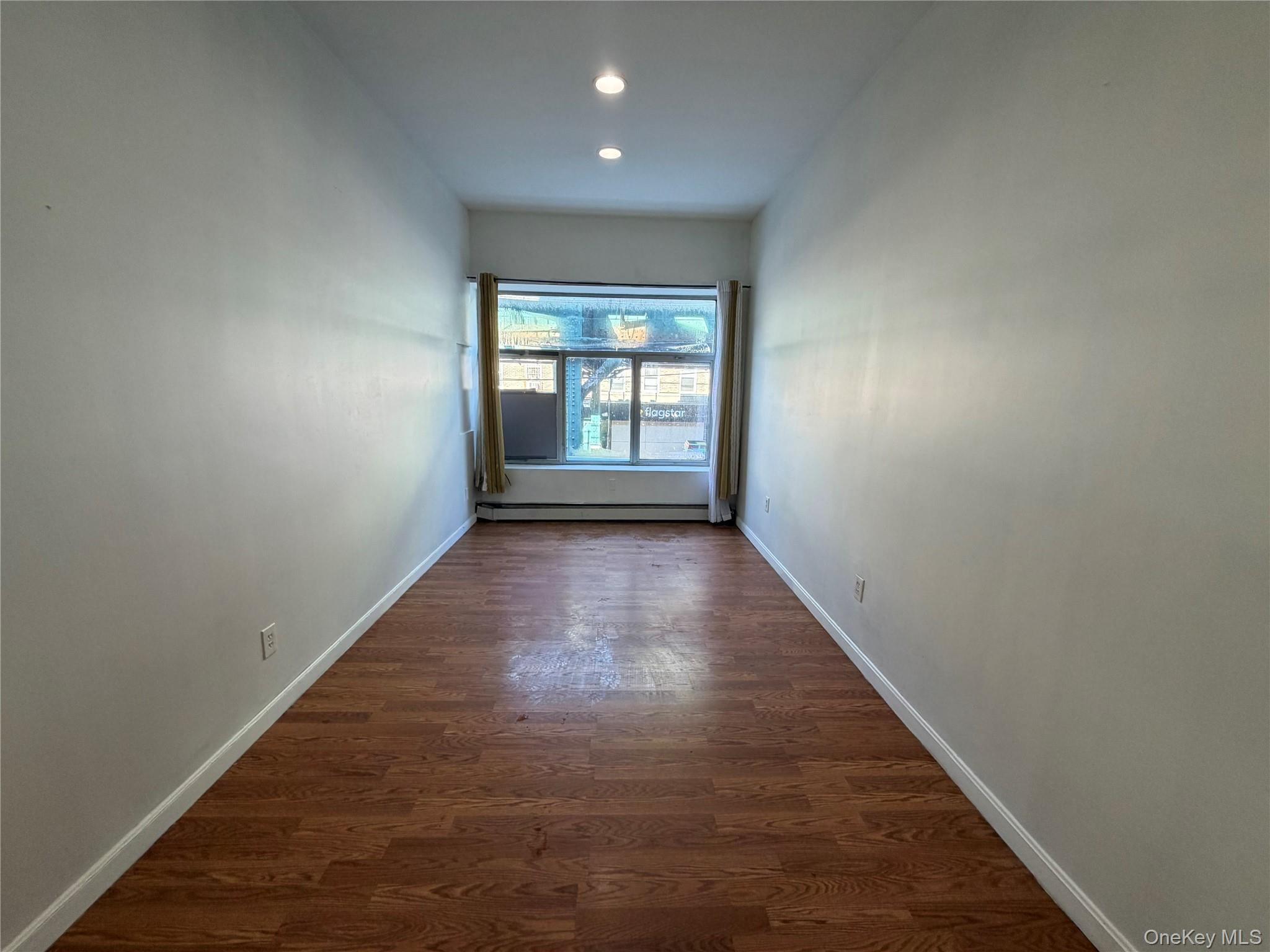86-28 80th Street Queens, NY 11421 - Photo 2 of 5 an empty room with wooden floor and windows