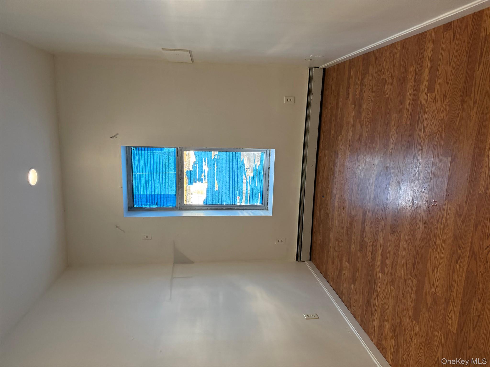 86-28 80th Street Queens, NY 11421 - Photo 5 of 5 a view of an empty room with wooden floor and a window