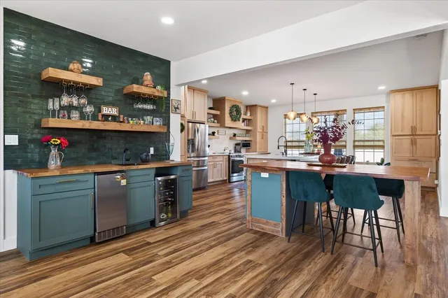 a kitchen with stainless steel appliances granite countertop a table chairs and a wooden floor