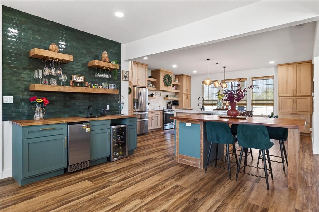 a kitchen with stainless steel appliances granite countertop a table chairs and a wooden floor
