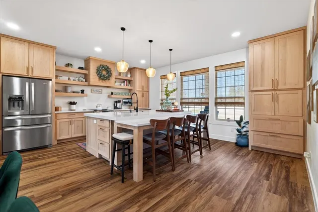 a kitchen with stainless steel appliances a dining table chairs stove refrigerator and wooden floor